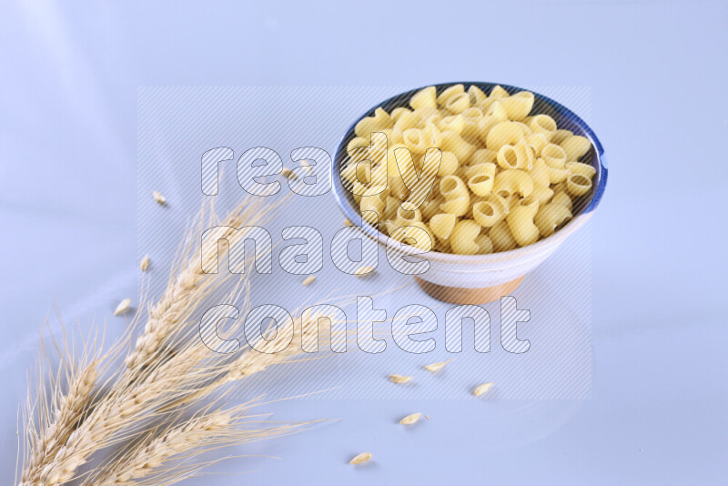 Raw pasta with wheat stalks on light blue background