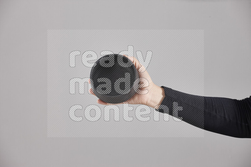 A woman in black abaya holding different pottery essentials in different positions