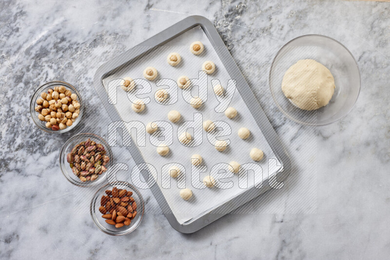 Ghoriba step by step with its ingredient, flour, powdered sugar, ghee and nuts on grey marble background