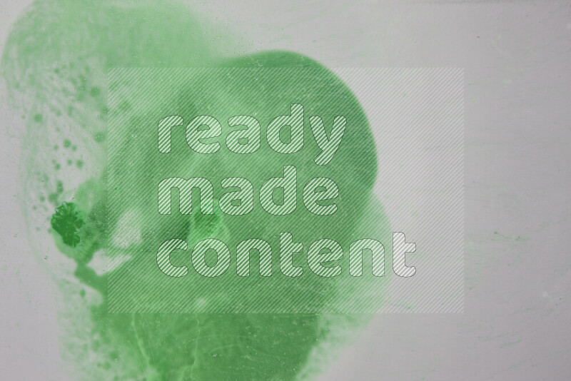 The image captures a dramatic splatter of green paint over a white backdrop