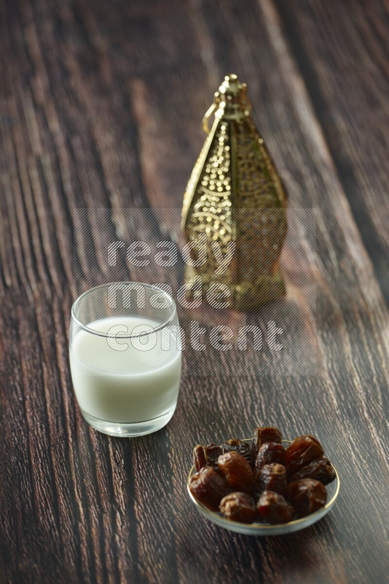 A golden lantern with different drinks, dates, nuts, prayer beads and quran on brown wooden background