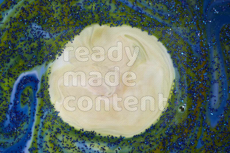 A close-up of sparkling blue glitter scattered on swirling blue and green background