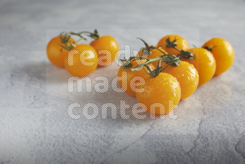 Yellow cherry tomato vein on a light grey textured background 45 degree