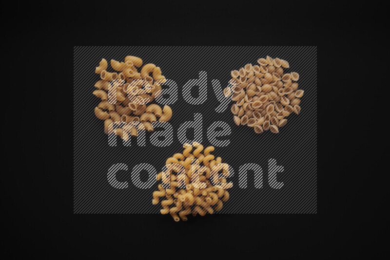 Different pasta types in bunches on black background