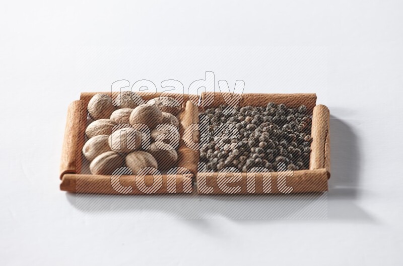 2 squares of cinnamon sticks full of black pepper and nutmegs on white flooring
