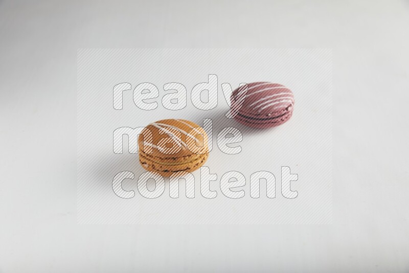 45º Shot of of two assorted Brown Irish Cream, and Red Poppy Flower macarons on white background