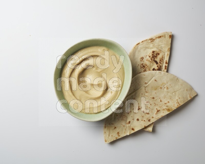 plain Hummus in a green plate on a white background