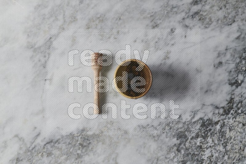 Multicolored pottery cup with wooden honey dipper on the side on grey marble background