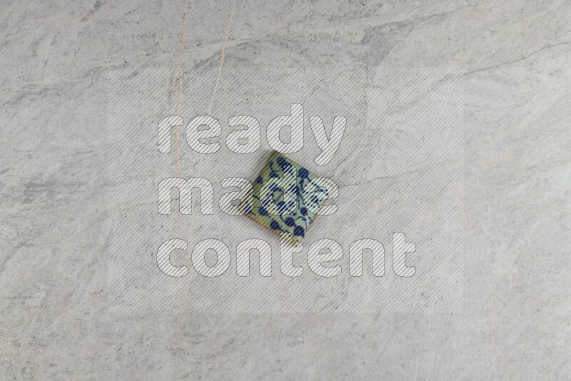 A decorative pottery coaster on grey marble background