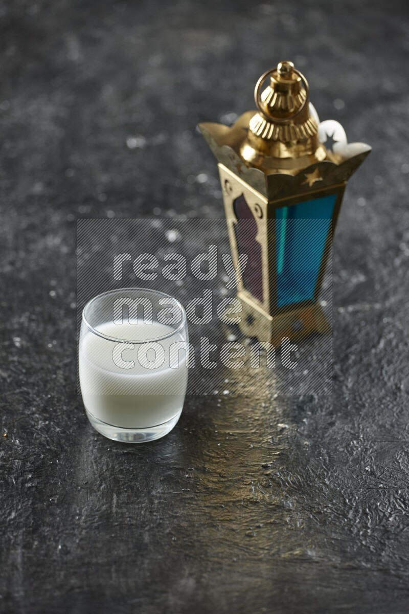 A golden lantern with different drinks, dates, nuts, prayer beads and quran on textured black background