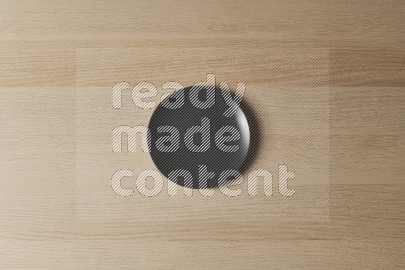 A black ceramic circular plate on light wooden background