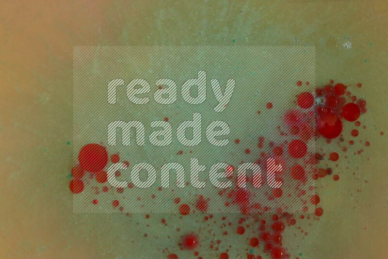 The image captures a dramatic splatter of red, green and yellow paints over the backdrop