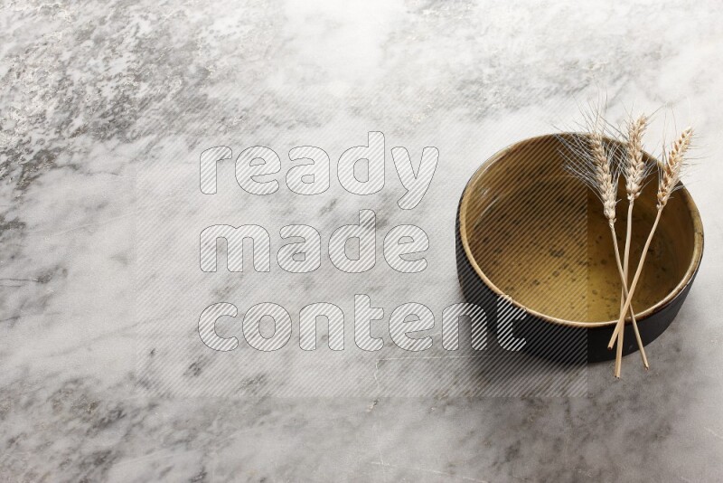 Wheat stalks on multicolored pottery oven plate on grey marble background