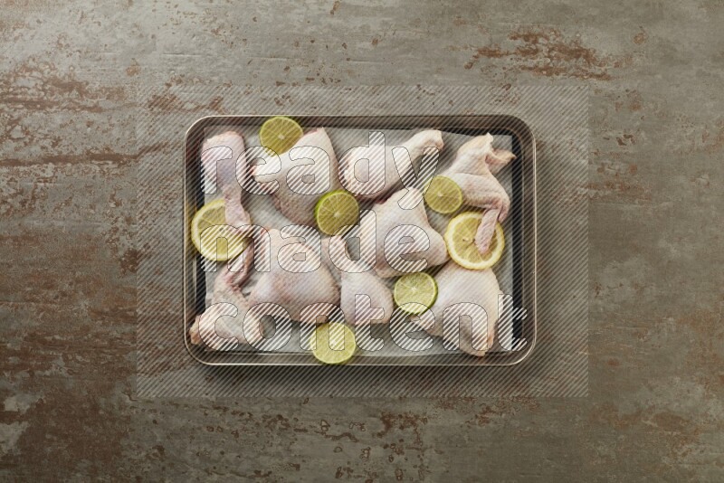 Mixed fresh chicken pieces in an oven tray on a textured rustic background