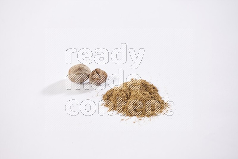 Nutmeg whole seeds with nutmeg powder beside it on a white flooring