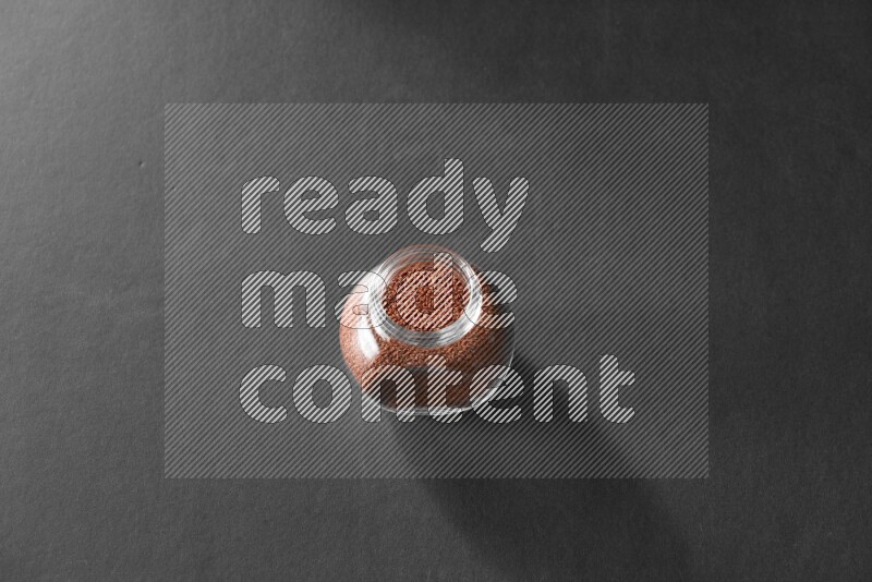 A glass spice jar full of garden cress on black flooring