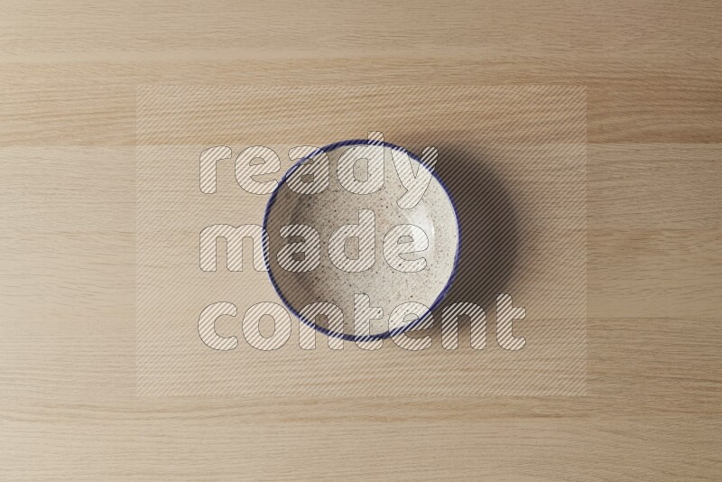 A multicolored pottery bowl on light wooden background
