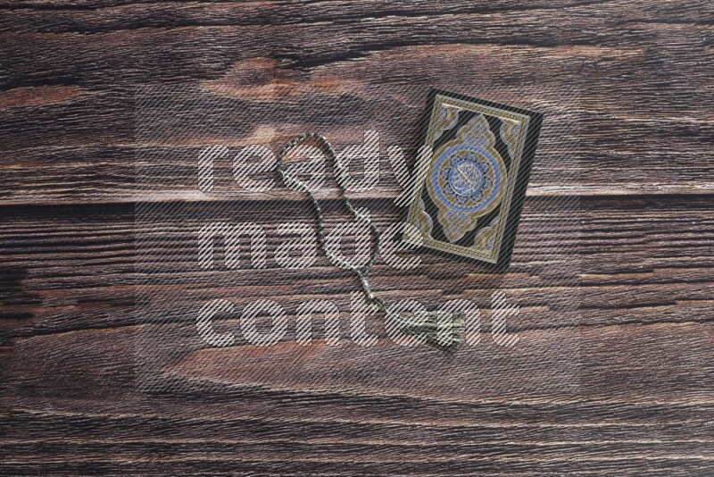 Quran with a prayer beads on wooden background