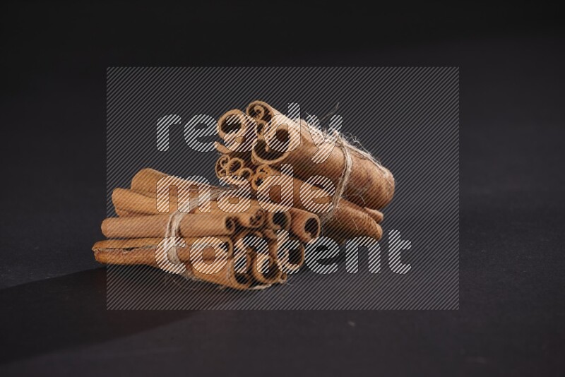 Two bounded stacks of cinnamon sticks on black background