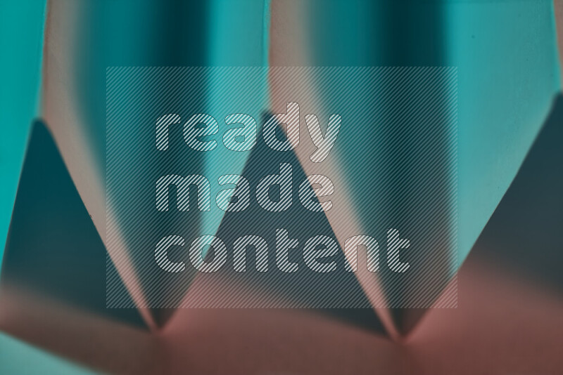 A close-up abstract image showing sharp geometric paper folds in green and red gradients