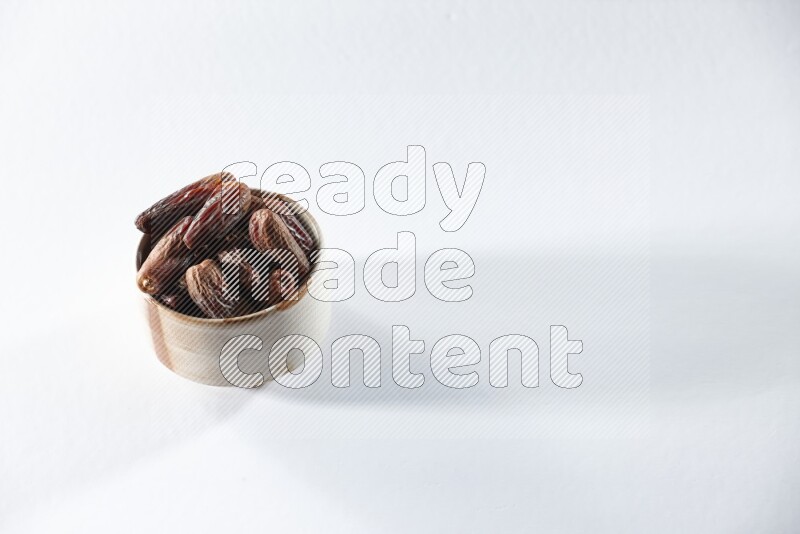 A beige ceramic bowl full of dried dates on a white background in different angles