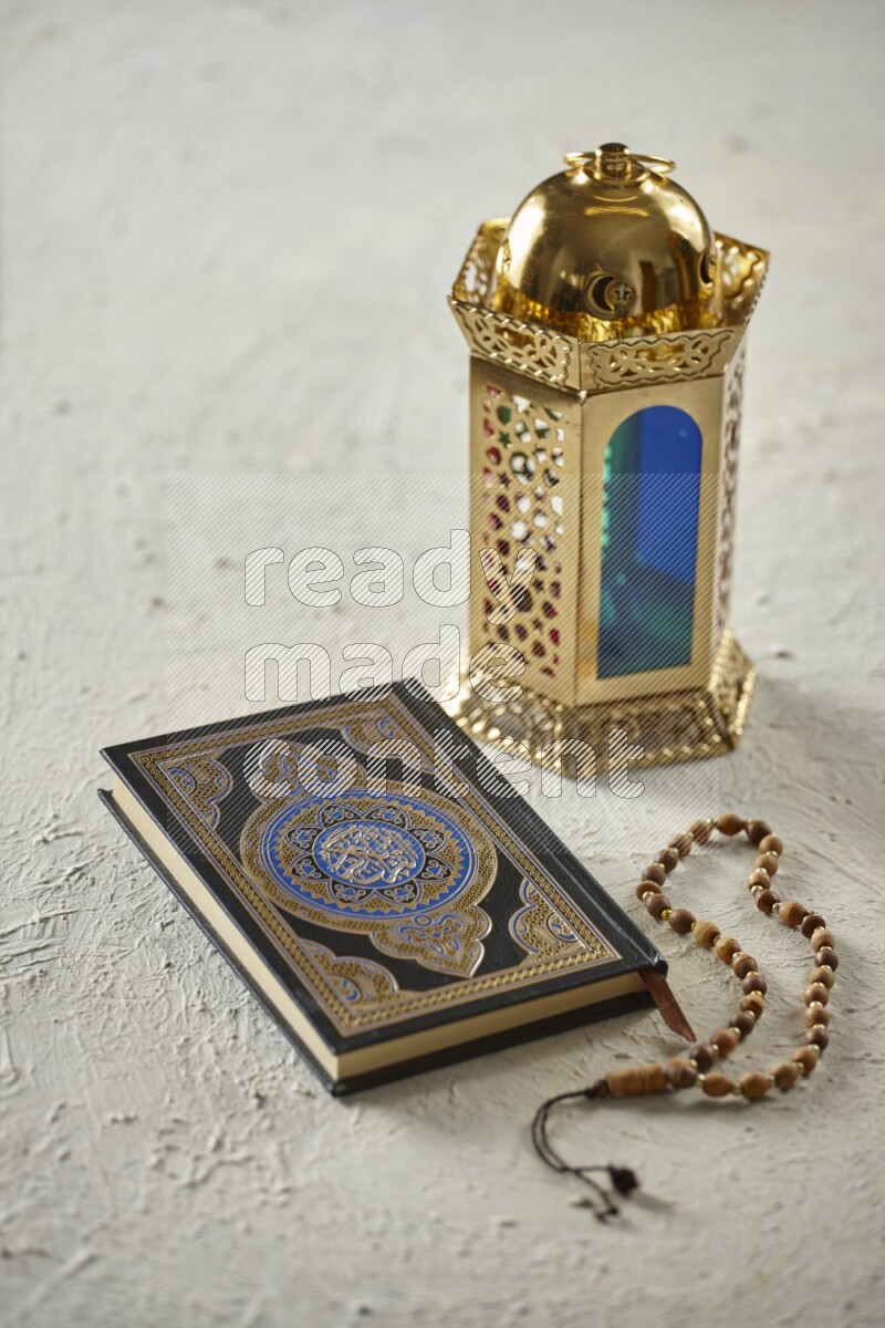 A golden lantern with different drinks, dates, nuts, prayer beads and quran on textured white background