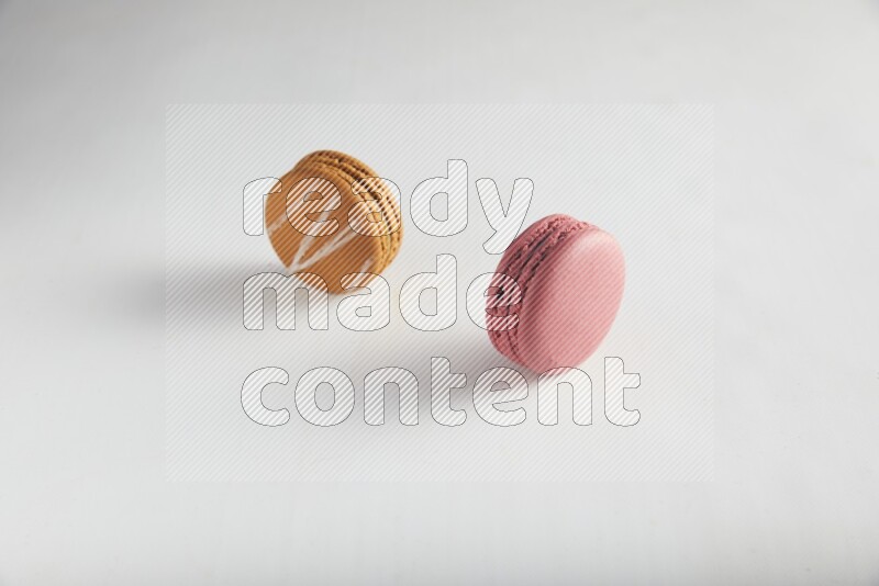 45º Shot of of two assorted Brown Irish Cream, and Pink Raspberry macarons on white background