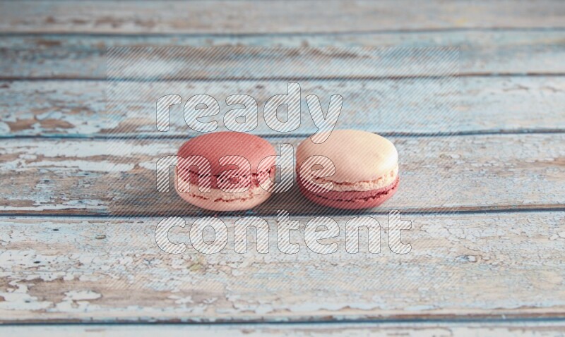 45º Shot of two Pink Litchi Raspberry macarons on light blue wooden background