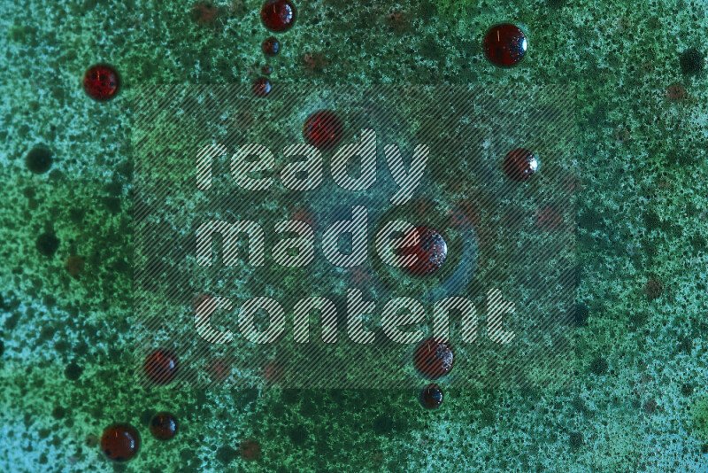 Close-ups of abstract red and green watercolor drops on oil Surface on green background