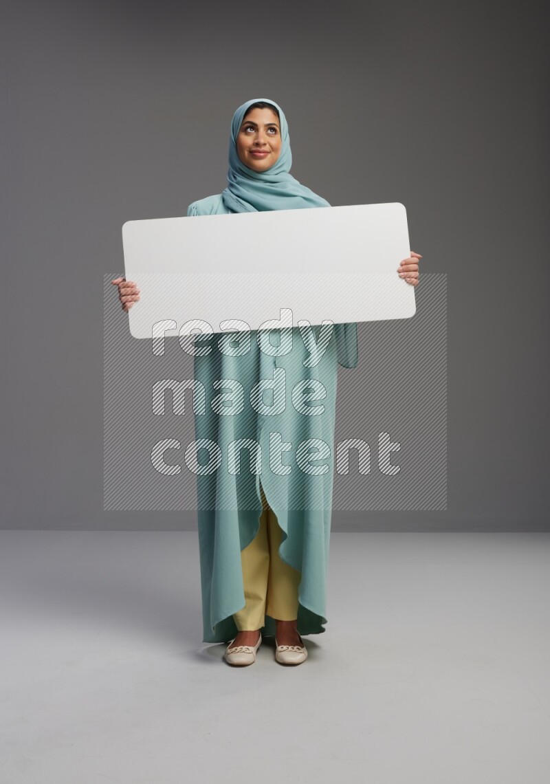 Saudi Woman wearing Abaya standing holding board on Gray background