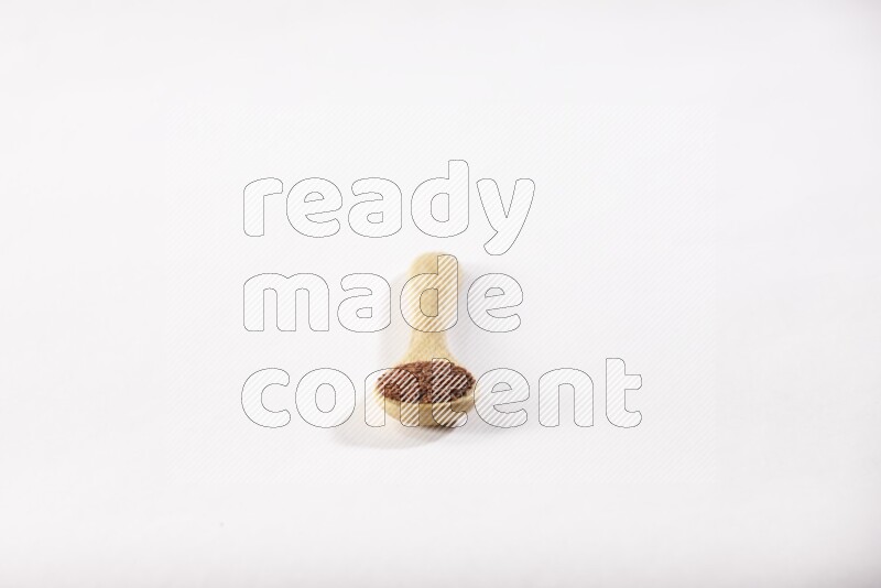A wooden spoon full of garden cress seeds on a white flooring