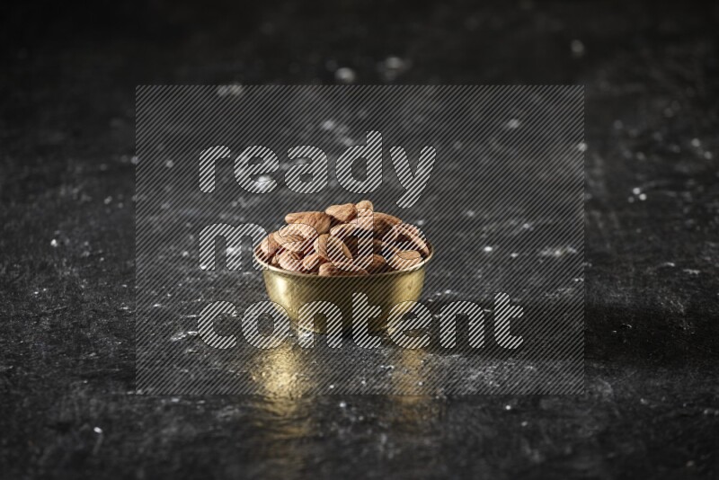 Nuts in a metal bowl in a dark setup