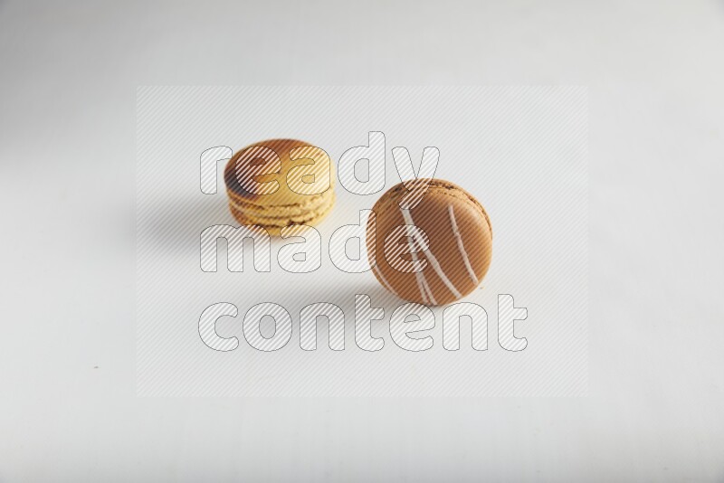 45º Shot of of two assorted Brown Irish Cream, and Yellow Crème Brulée macarons on white background