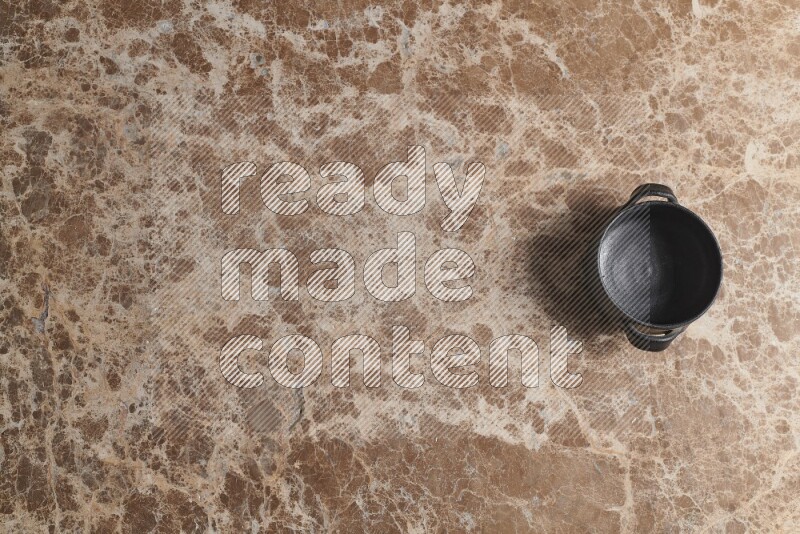 A black pottery bowl on beige marble background
