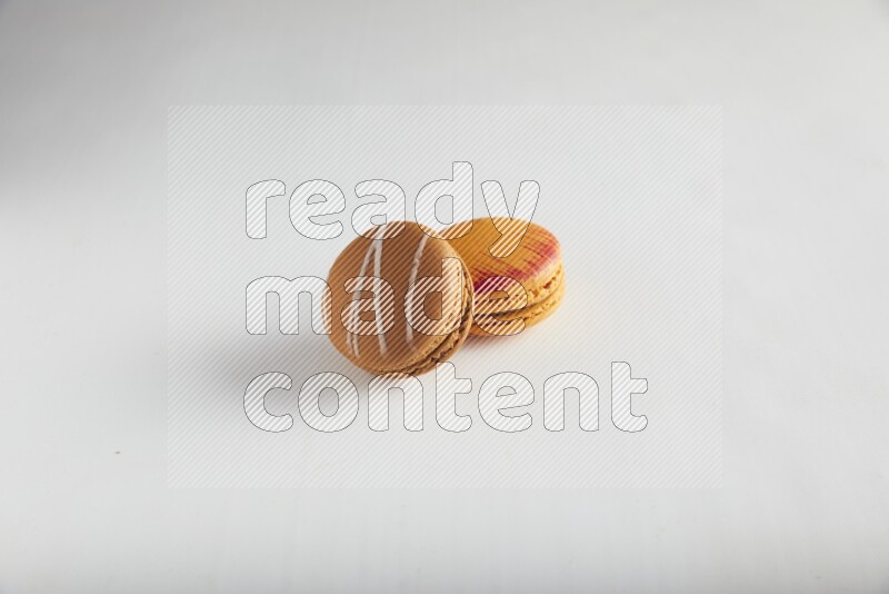 45º Shot of of two assorted Brown Irish Cream, and Orange Exotic macarons on white background