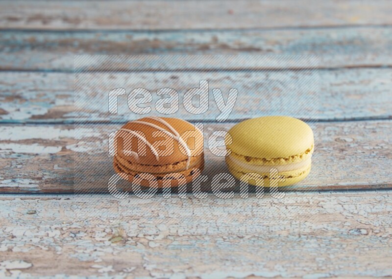 45º Shot of of two assorted Brown Irish Cream, and Yellow Lime macarons on light blue background