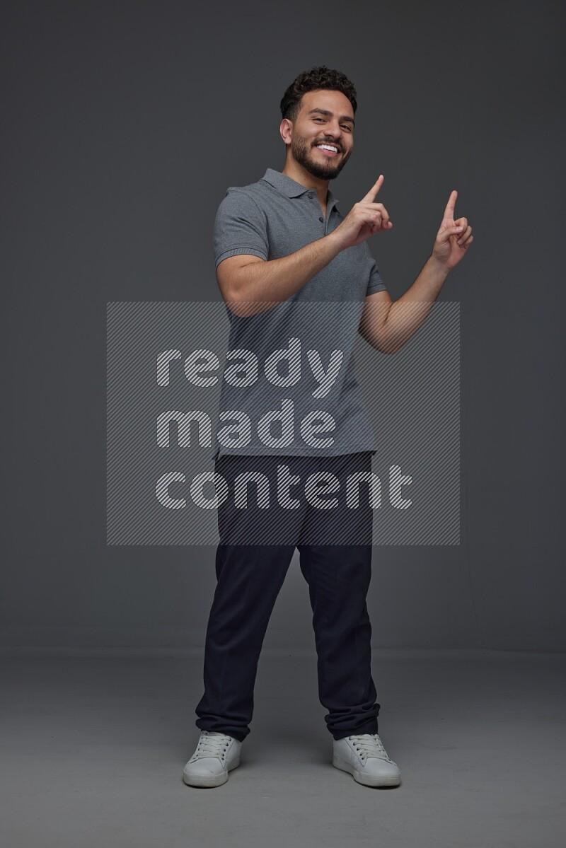 A man wearing casual standing and making multi hand gestures eye level on a gray background