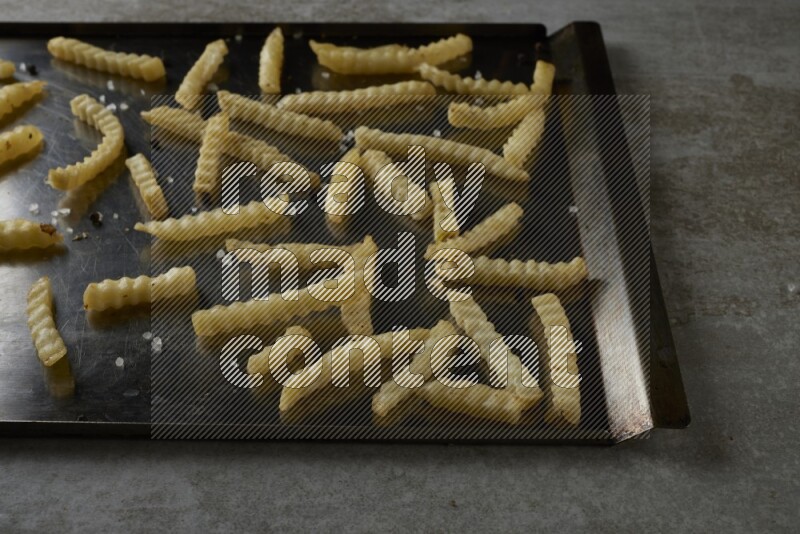 crinkle fries in a black stainless steel rectangle tray on grey textured counter top