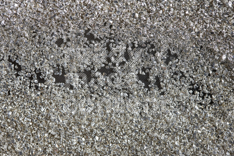 Silver shimmering fragments of glass scattered on a black background