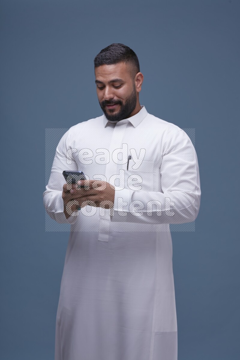 A man Texting on Blue Background wearing Saudi Thob