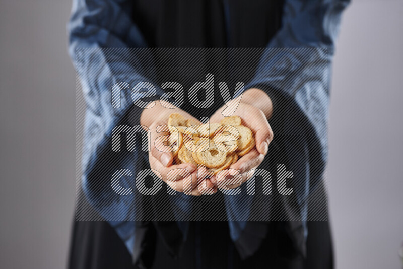 Woman in abaya holding different kinds of snacks in different positions