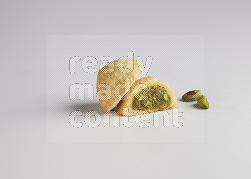 Two Pieces of Maamoul filled with pistachio paste  one of them is cut direct on white background