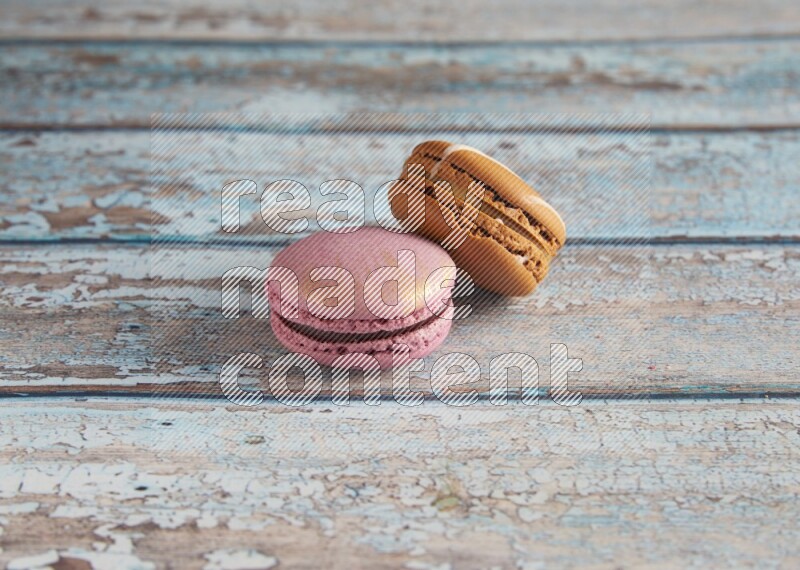 45º Shot of of two assorted Brown Irish Cream, and Purple Strawberry macarons  on light blue background
