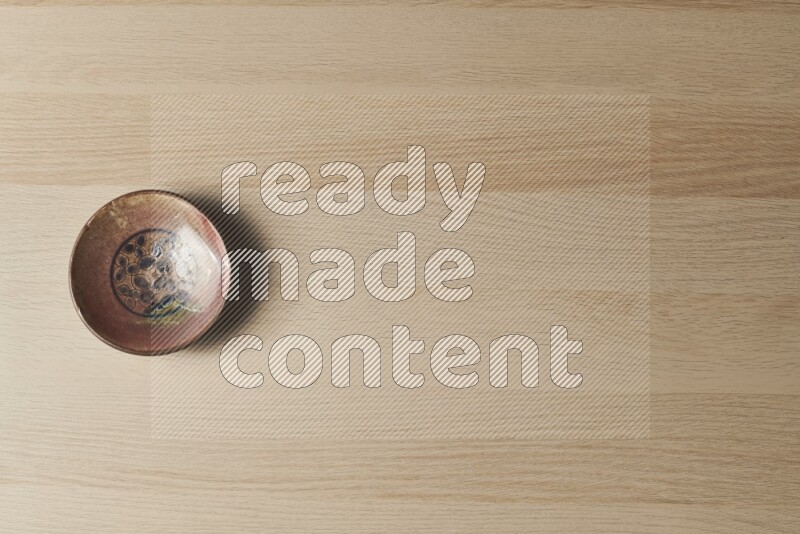 A decorative pottery plate on light wooden background