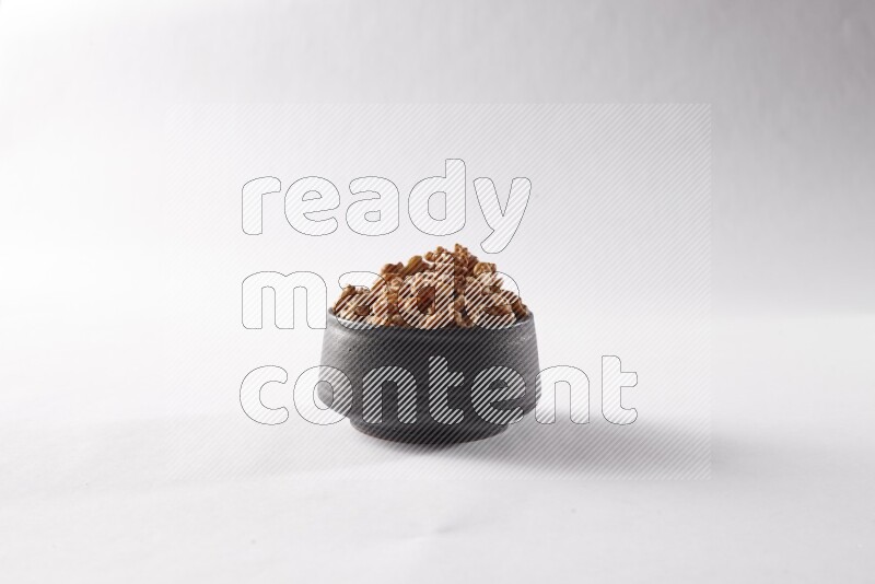 Walnuts in a black pottery bowl on white background