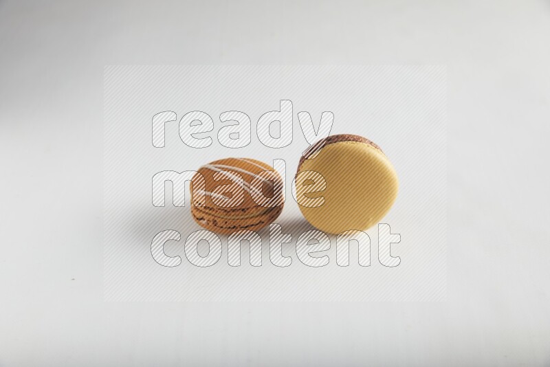 45º Shot of of two assorted Brown Irish Cream, and Yellow, and Brown Chai Latte macarons on white background
