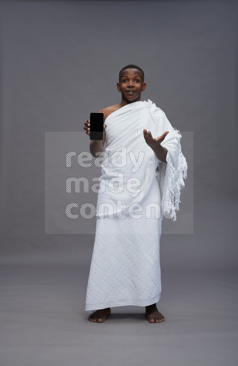 A man wearing Ehram Standing showing phone to camera on gray background