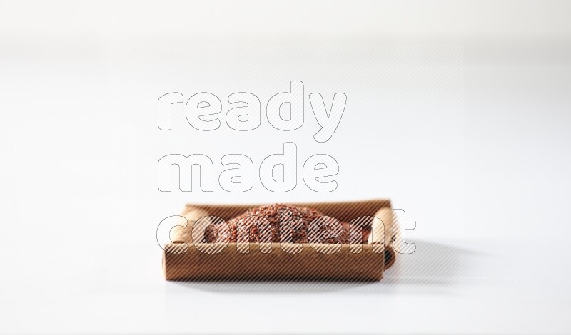 أربعة من أعواد القرفة مكونة شكل مربع بداخلها حب الرشاد علي خلفية بيضاء