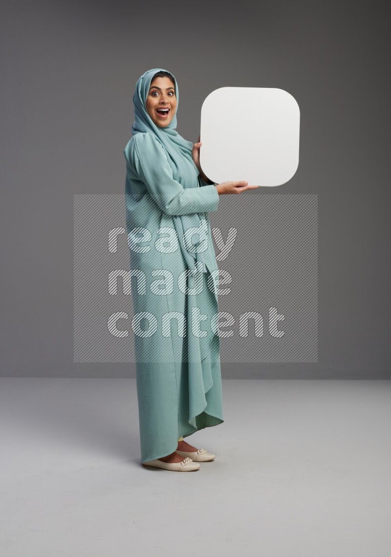 Saudi Woman wearing Abaya standing holding social media sign on Gray background