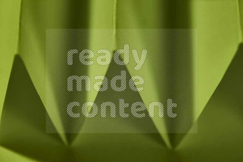 صورة مجردة مقربة تظهر طيات ورقية هندسية حادة بتدرجات اللون الأخضر